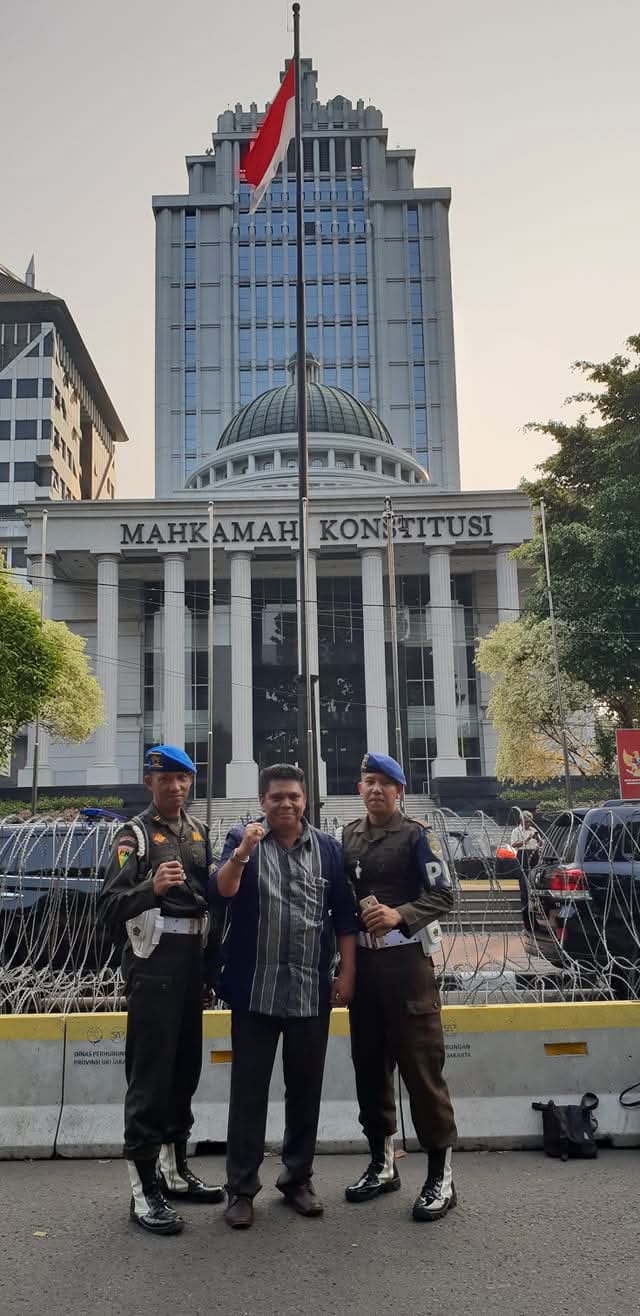 Momen Raymond Simamora, S.H., M.H. berpose bersama dua personel keamanan di depan gedung Mahkamah Konstitusi Republik Indonesia di Jakarta Pusat.