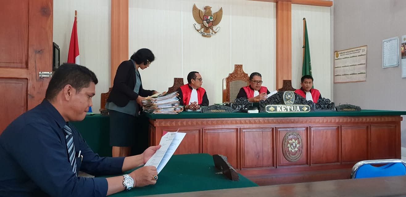 Momen Raymond Simamora, S.H., M.H. saat mencermati berkas perkara dalam sebuah agenda persidangan yang dipimpin oleh majelis hakim di ruang sidang utama.