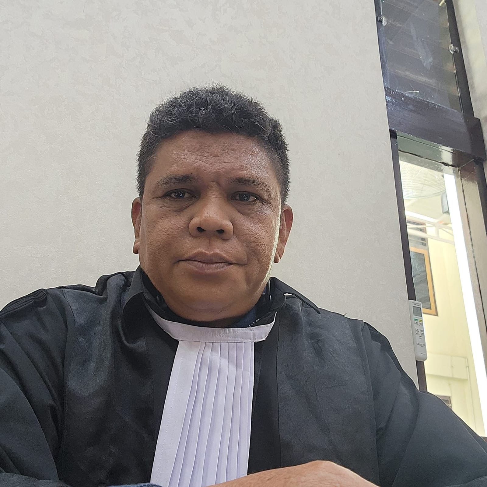 Potret Raymond Simamora, S.H., M.H. dalam balutan toga advokat lengkap saat berada di dalam ruang sidang.